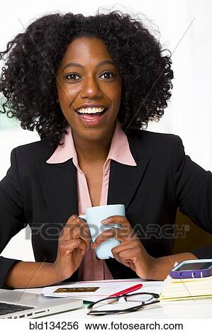 Mixed race businesswoman drinking coffee at desk View Large Photo Image Stock Photograph - Mixed race businesswoman drinking coffee at desk. Fotosearch