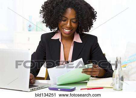 Mixed race businesswoman reading papers at desk View Large Photo Image Stock Image - Mixed race businesswoman reading papers at desk. Fotosearch