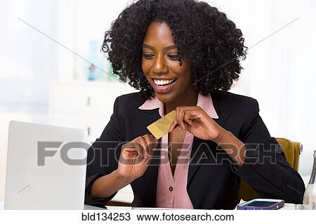 Mixed race businesswoman shopping on laptop at desk View Large Photo Image Stock Image - Mixed race businesswoman shopping on laptop at desk. Fotosearch