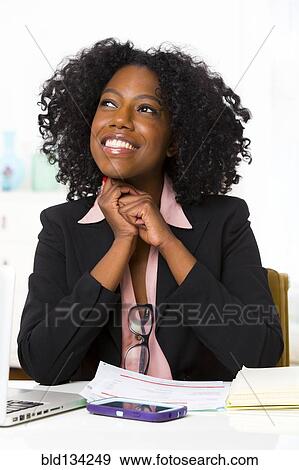Stock Photo - Mixed race businesswoman sitting at desk. Fotosearch