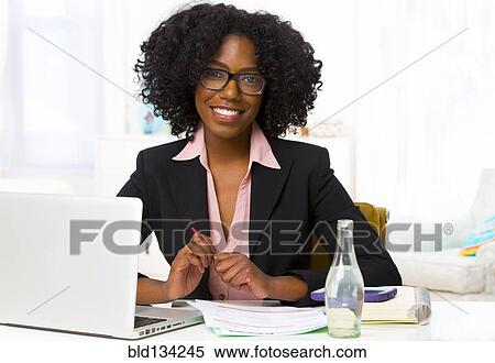 Mixed race businesswoman smiling at desk View Large Photo Image Stock Photography - Mixed race businesswoman smiling at desk. Fotosearch