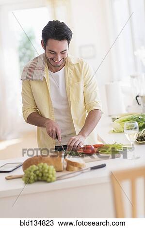 Stock Image - Mixed race man cooking in kitchen. Fotosearch