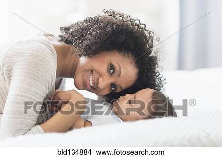 Mixed race mother playing with baby on bed View Large Photo Image Picture - Mixed race mother playing with baby on bed. Fotosearch