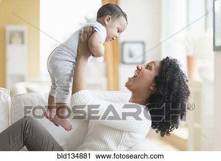 Mixed race mother playing with baby on sofa View Large Photo Image Stock Image - Mixed race mother playing with baby on sofa. Fotosearch