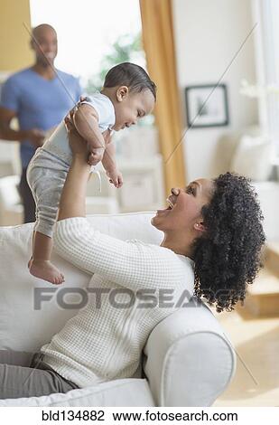 Mixed race mother playing with baby on sofa View Large Photo Image Stock Image - Mixed race mother playing with baby on sofa. Fotosearch