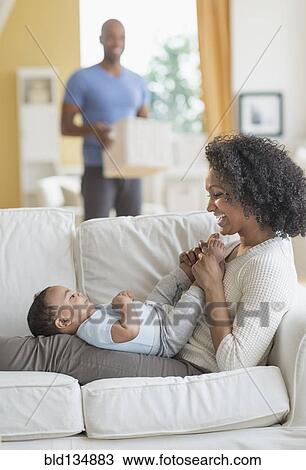 Mixed race mother playing with baby on sofa View Large Photo Image Stock Image - Mixed race mother playing with baby on sofa. Fotosearch