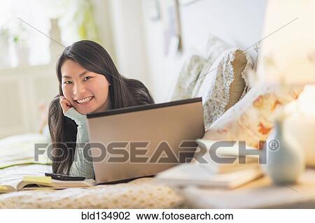 Mixed race teenage girl doing homework on bed View Large Photo Image Stock Image - Mixed race teenage girl doing homework on bed. Fotosearch