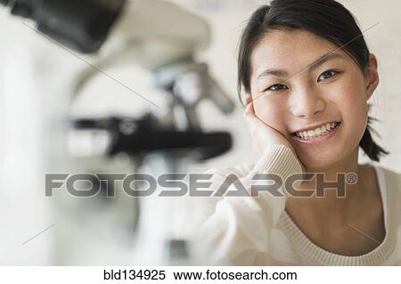 Stock Photography - Mixed race teenage girl smiling in science lab. Fotosearch