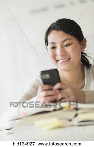 Stock Photo - Mixed race teenage girl using cell phone in class. Fotosearch