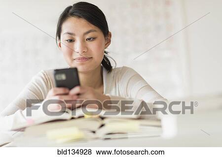 Stock Photo - Mixed race teenage girl using cell phone in class. Fotosearch