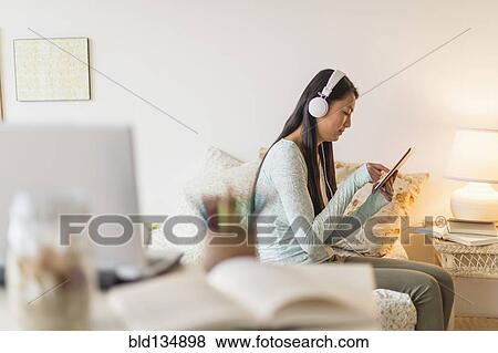 Stock Photo - Mixed race teenage girl using digital tablet on bed. Fotosearch
