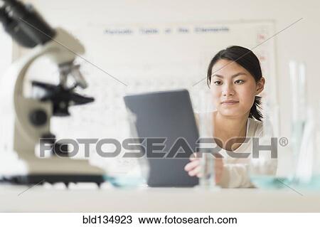 Stock Image - Mixed race teenage girl using laptop computer in science lab. Fotosearch