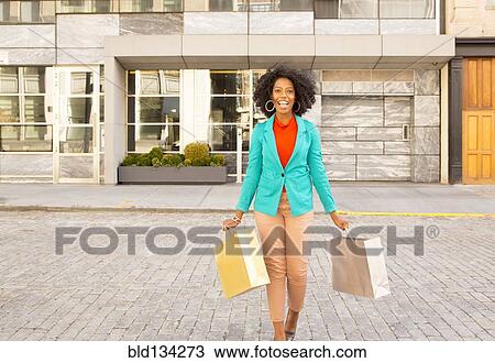 Mixed race woman carrying shopping bags on city street View Large Photo Image Stock Image - Mixed race woman carrying shopping bags on city street. Fotosearch
