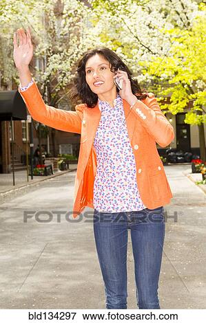 Stock Photo - Mixed race woman hailing taxi on city street. Fotosearch