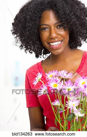Stock Image - Mixed race woman holding bouquet of flowers. Fotosearch