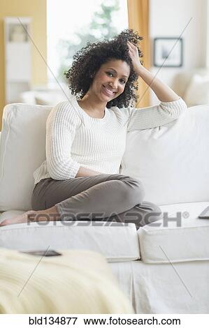 Stock Photo - Mixed race woman smiling on sofa. Fotosearch