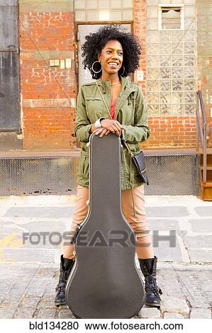 Mixed race woman with guitar case on city street View Large Photo Image Stock Image - Mixed race woman with guitar case on city street. Fotosearch