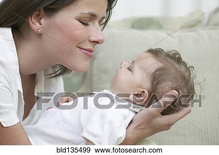 Mother admiring baby on sofa View Large Photo Image Stock Photo - Mother admiring baby on sofa. Fotosearch