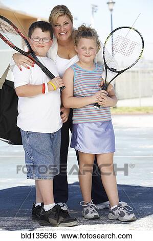 Mother and children holding tennis rackets outdoors View Large Photo Image Stock Photograph - Mother and children holding tennis rackets outdoors. Fotosearch