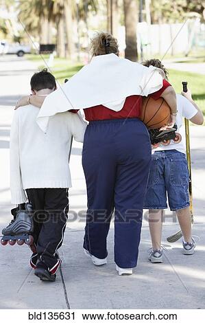 Stock Image - Mother and children walking on suburban street. Fotosearch