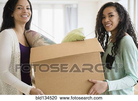 Stock Image - Mother and daughter carrying cardboard box. Fotosearch