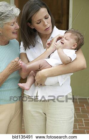 Mother and daughter comforting crying baby View Large Photo Image Stock Image - Mother and daughter comforting crying baby. Fotosearch