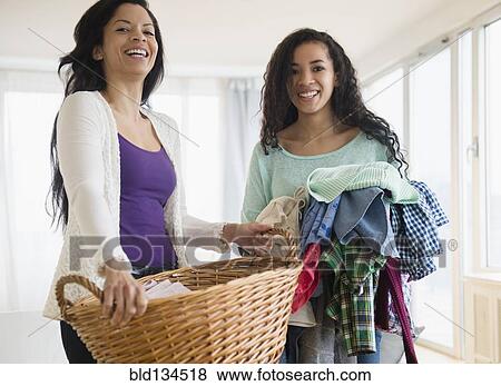 Stock Photo - Mother and daughter holding laundry. Fotosearch