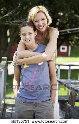 Mother and daughter hugging on patio View Large Photo Image Stock Image - Mother and daughter hugging on patio. Fotosearch