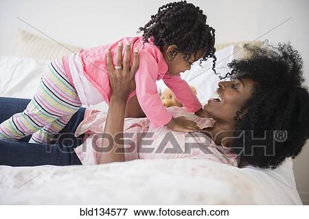 Stock Photo - Mother and daughter playing on bed. Fotosearch