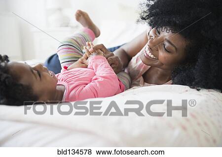 Mother and daughter playing on bed View Large Photo Image Stock Photo - Mother and daughter playing on bed. Fotosearch