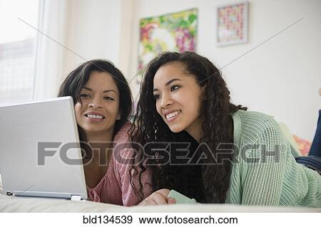 Stock Photo - Mother and daughter using laptop on bed. Fotosearch