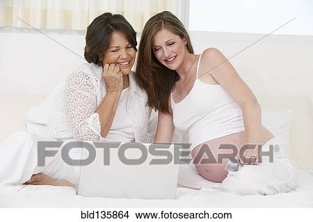 Mother and pregnant daughter using laptop View Large Photo Image Picture - Mother and pregnant daughter using laptop. Fotosearch