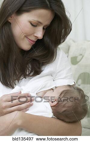 Mother breastfeeding baby on sofa View Large Photo Image Stock Photo - Mother breastfeeding baby on sofa. Fotosearch