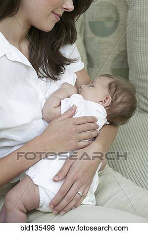 Mother breastfeeding baby on sofa View Large Photo Image Stock Photo - Mother breastfeeding baby on sofa. Fotosearch
