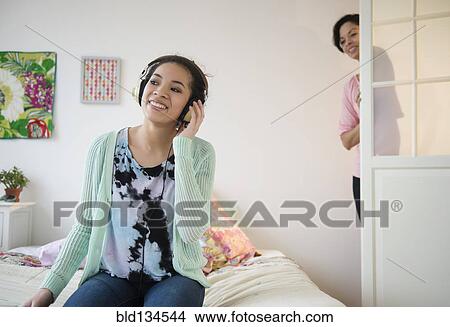 Mother checking on teenage girl listening to headphones View Large Photo Image Picture - Mother checking on teenage girl listening to headphones. Fotosearch