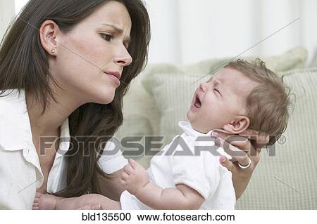 Mother comforting crying baby on sofa View Large Photo Image Stock Image - Mother comforting crying baby on sofa. Fotosearch