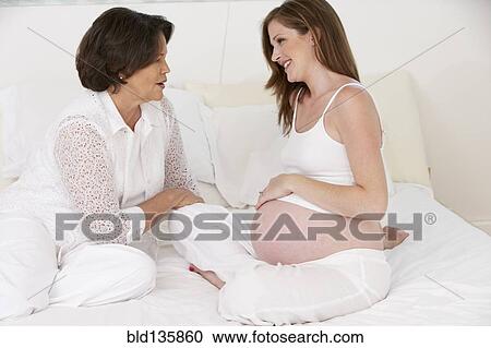 Stock Image - Mother examining daughter's pregnant belly. Fotosearch