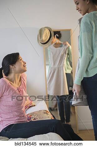 Stock Photography - Mother helping daughter choose dress. Fotosearch