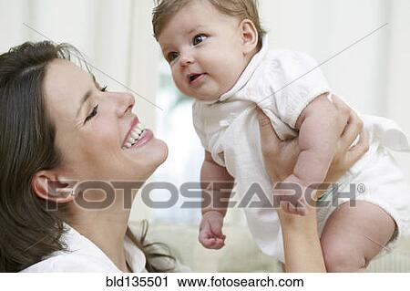 Mother holding baby on sofa View Large Photo Image Stock Image - Mother holding baby on sofa. Fotosearch