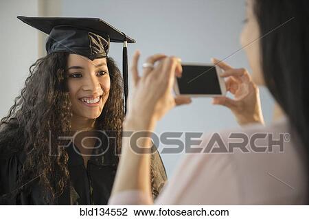 Mother photographing daughter at graduation View Large Photo Image Stock Image - Mother photographing daughter at graduation. Fotosearch