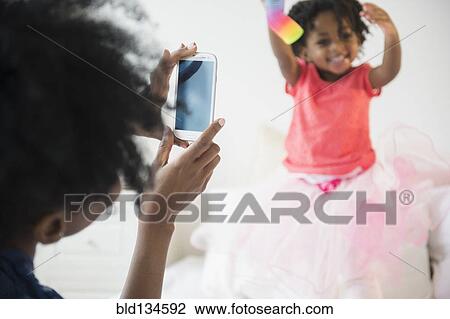 Stock Image - Mother photographing daughter. Fotosearch