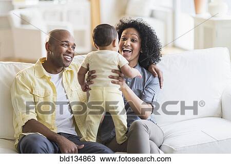 Parents playing with baby in living room View Large Photo Image Stock Image - Parents playing with baby in living room. Fotosearch