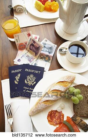 Passports, money and food on breakfast table View Large Photo Image Stock Image - Passports, money and food on breakfast table. Fotosearch