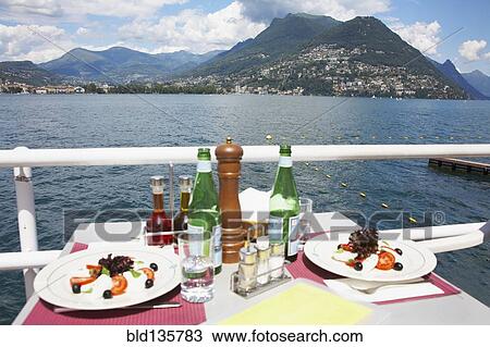 Plates of food at restaurant overlooking rural lake, Lugano, Ticino, Switzerland View Large Photo Image Stock Image - Plates of food at restaurant overlooking rural lake, Lugano, Ticino, Switzerland. Fotosearch