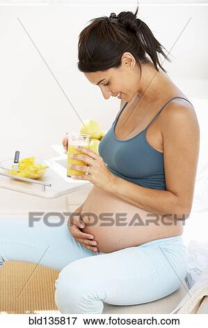 Stock Photo - Pregnant Hispanic woman drinking fruit juice. Fotosearch