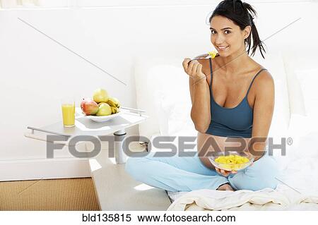 Stock Photography - Pregnant Hispanic woman eating fruit. Fotosearch