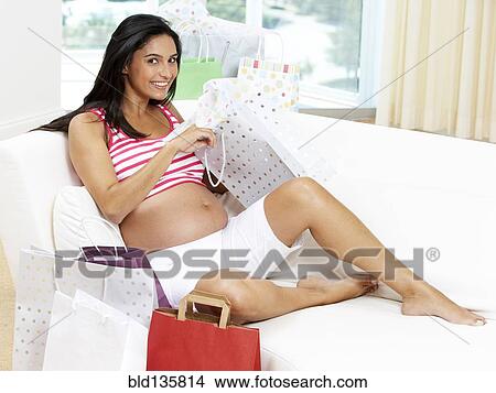 Picture - Pregnant Hispanic woman opening gifts. Fotosearch