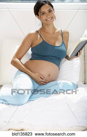 Pregnant Hispanic woman reading in bed View Large Photo Image Stock Image - Pregnant Hispanic woman reading in bed. Fotosearch