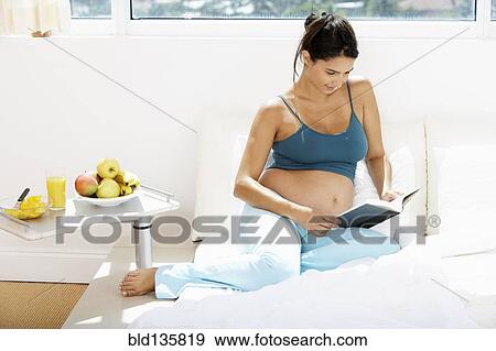 Pregnant Hispanic woman reading in bed View Large Photo Image Stock Photo - Pregnant Hispanic woman reading in bed. Fotosearch