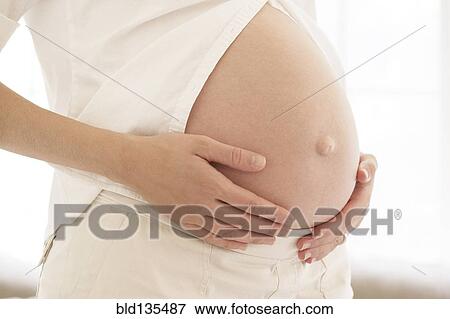 Stock Photo - Pregnant woman holding her belly. Fotosearch